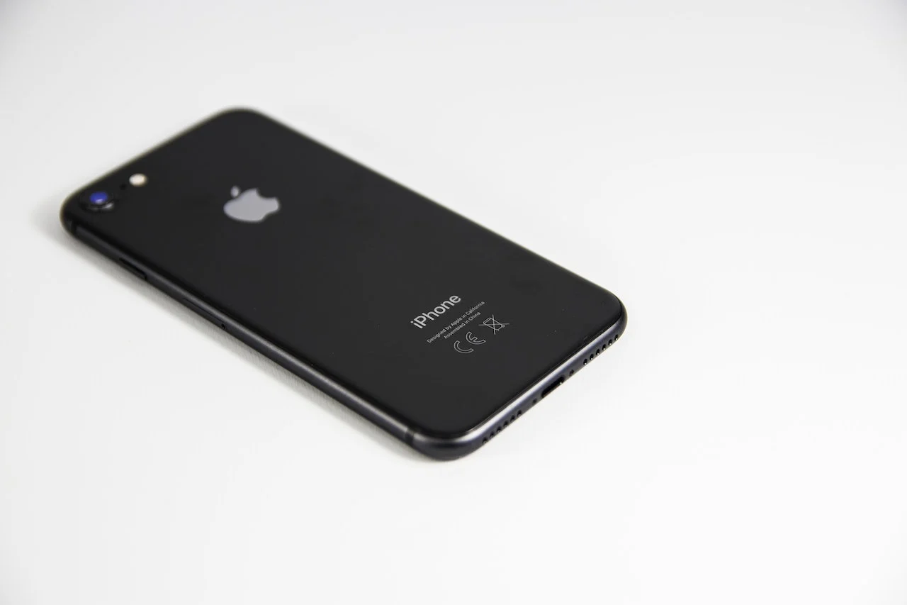 A close-up image showcasing an iPhone 8 placed on a wooden table, its screen glowing with a display of apps, set against a backdrop that subtly captures the essence of Norwegian lifestyle, featuring minimalist furniture and hints of traditional design elements